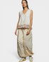 Woman wearing a sleeveless top with floral pattern and wide-leg pants on a white background