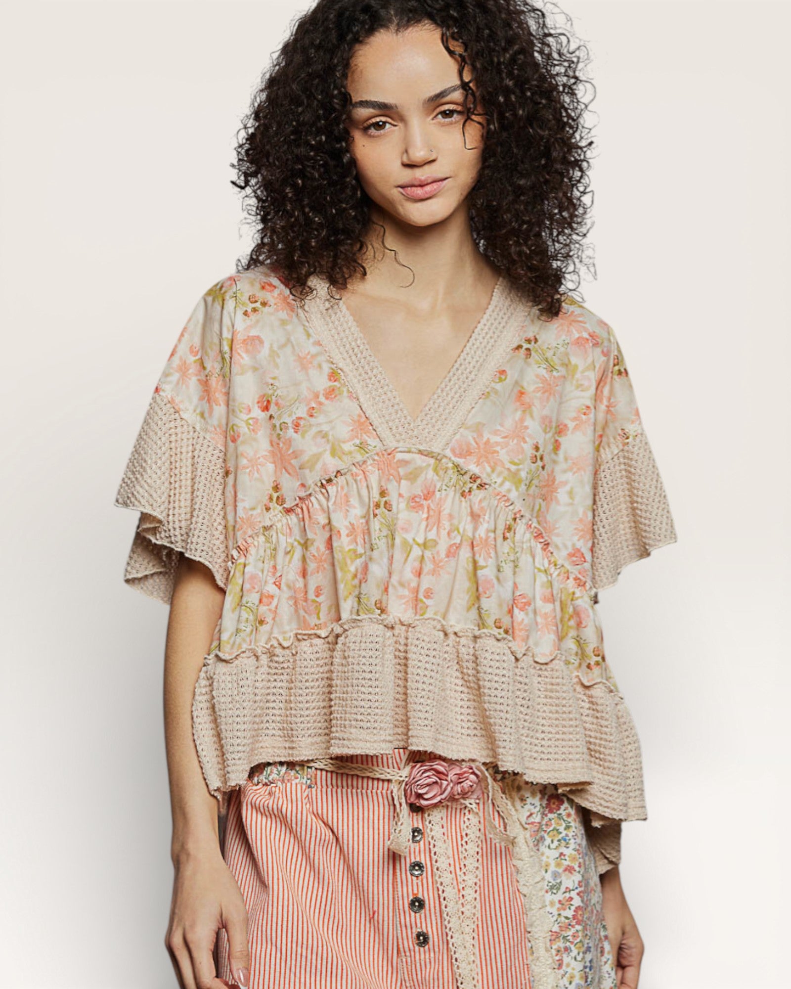 Woman wearing a floral blouse with ruffled details on a plain background