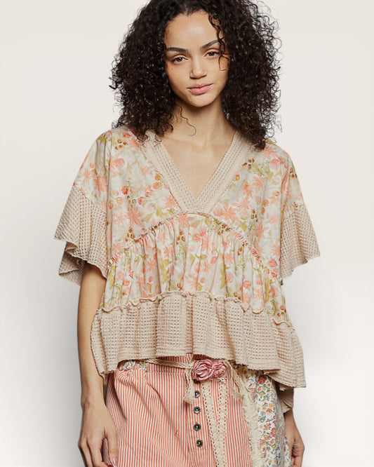 Woman wearing a floral blouse with ruffled details on a plain background