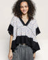 Woman wearing a floral blouse with black ruffled sleeves on a plain background