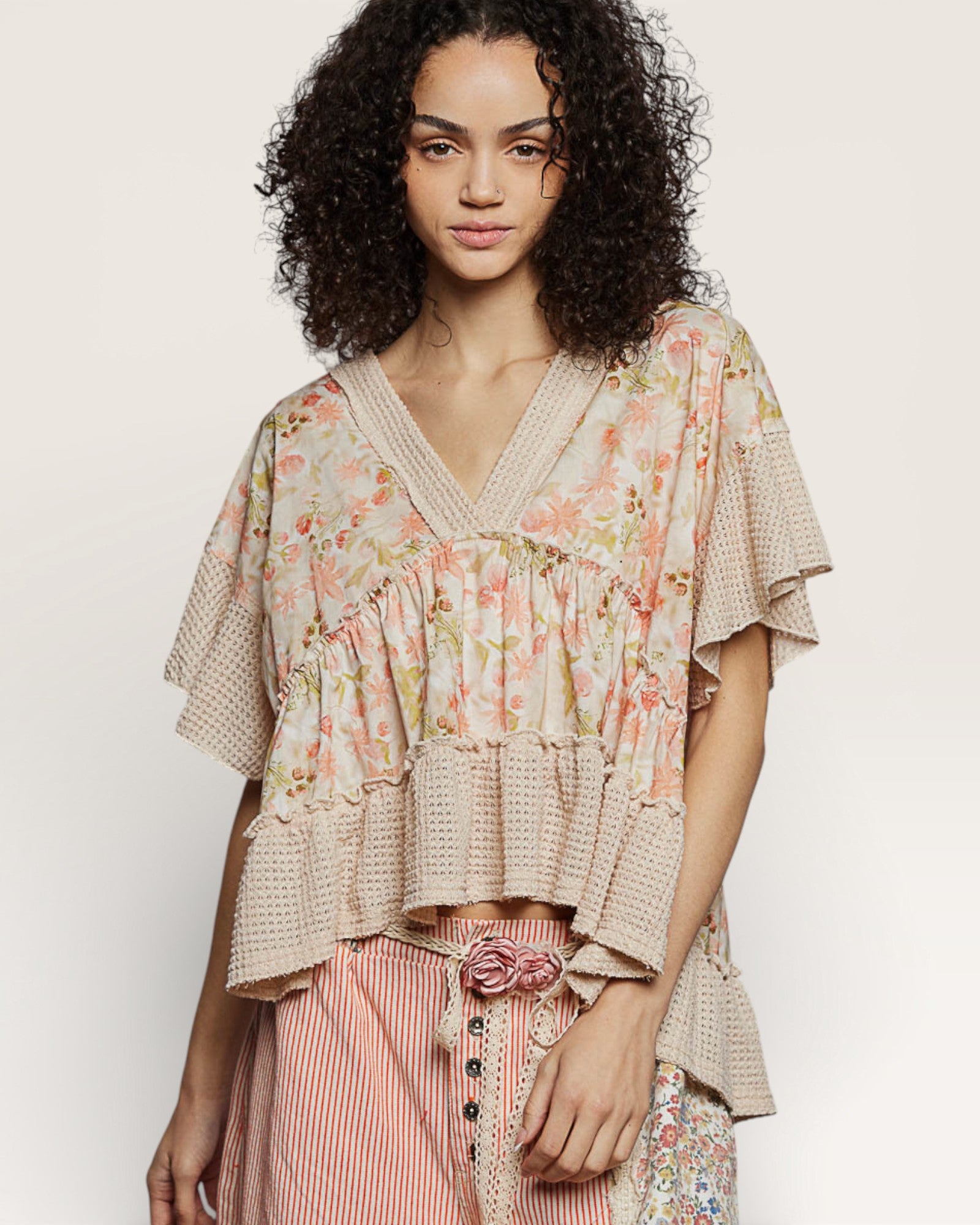 Woman wearing a floral blouse with ruffled sleeves on a plain background