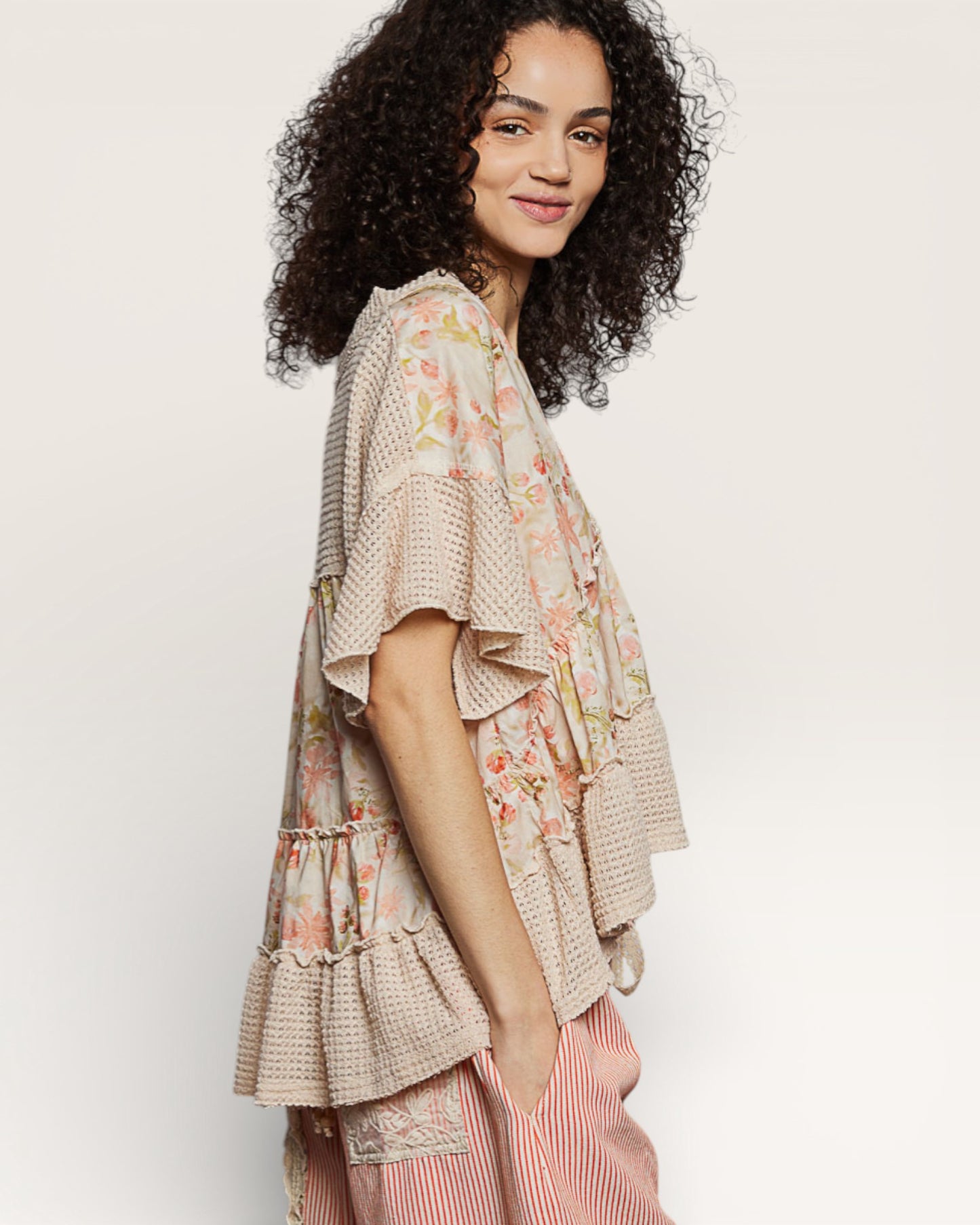 Woman wearing a floral and ruffled top with a plain background