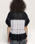 Person wearing a black and floral layered top on a plain background