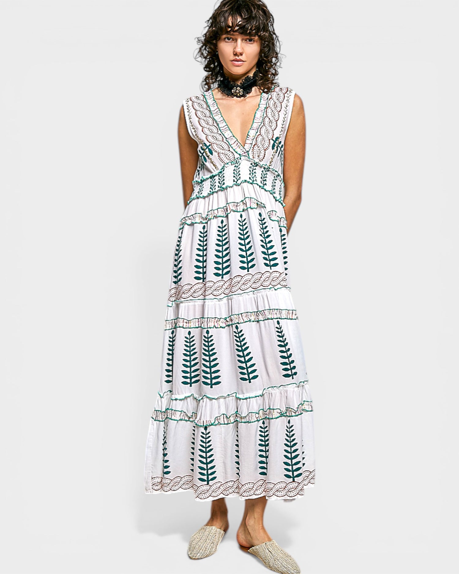 Woman wearing a white dress with green leaf patterns on a plain background