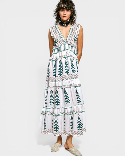 Woman wearing a white dress with green leaf patterns on a plain background