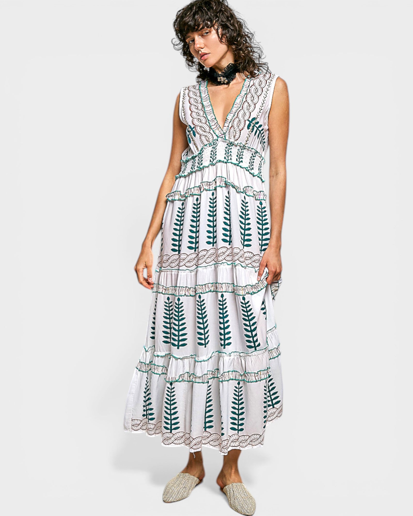Woman wearing a white dress with green leaf patterns on a white background