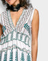White dress with green leaf patterns worn by a person on a plain background
