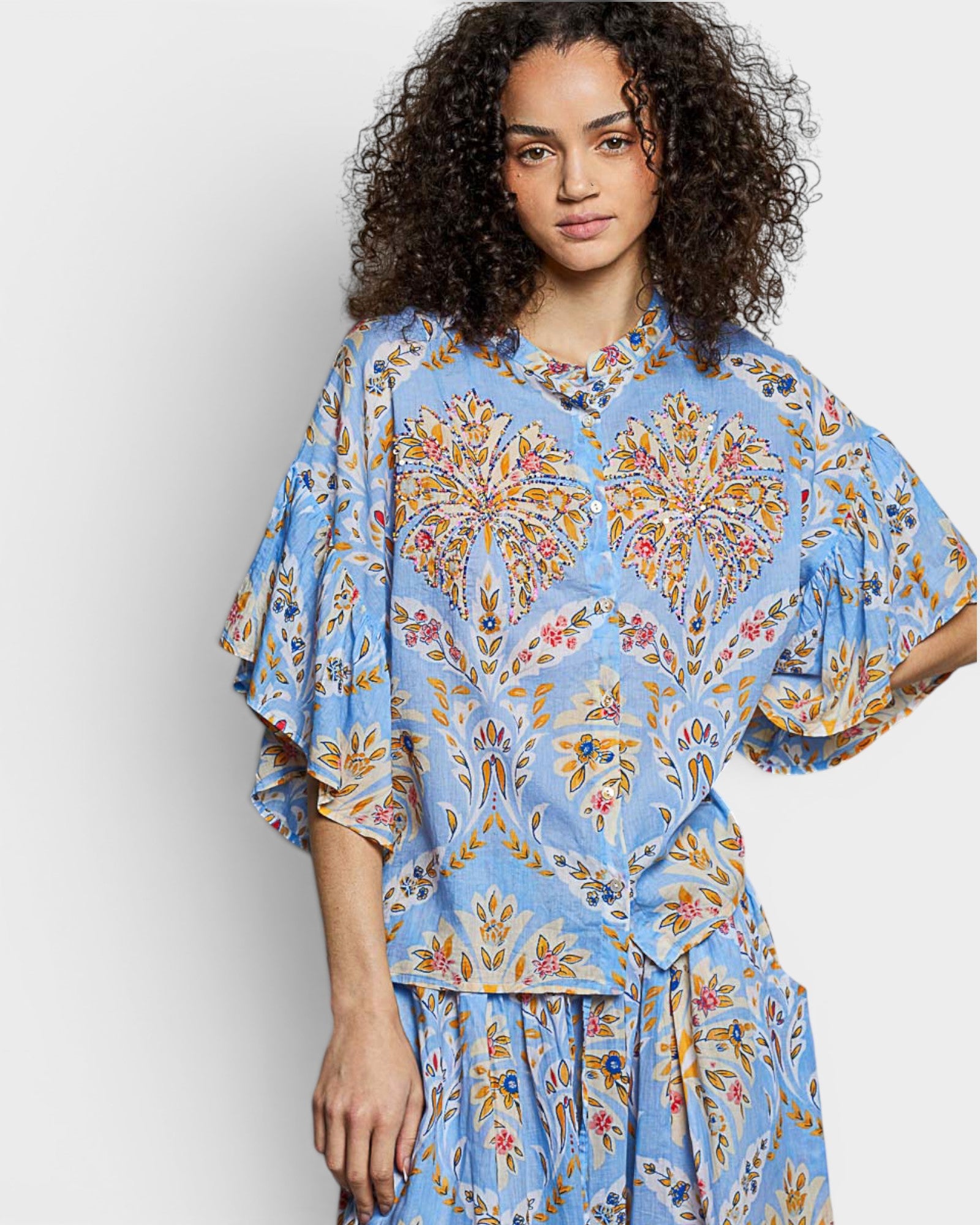 Woman wearing a blue floral outfit against a white background
