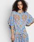 Woman wearing a blue floral outfit against a white background