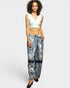 Woman wearing a white sleeveless top and patterned pants on a white background
