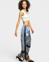 Woman wearing a white top and patterned pants on a plain background