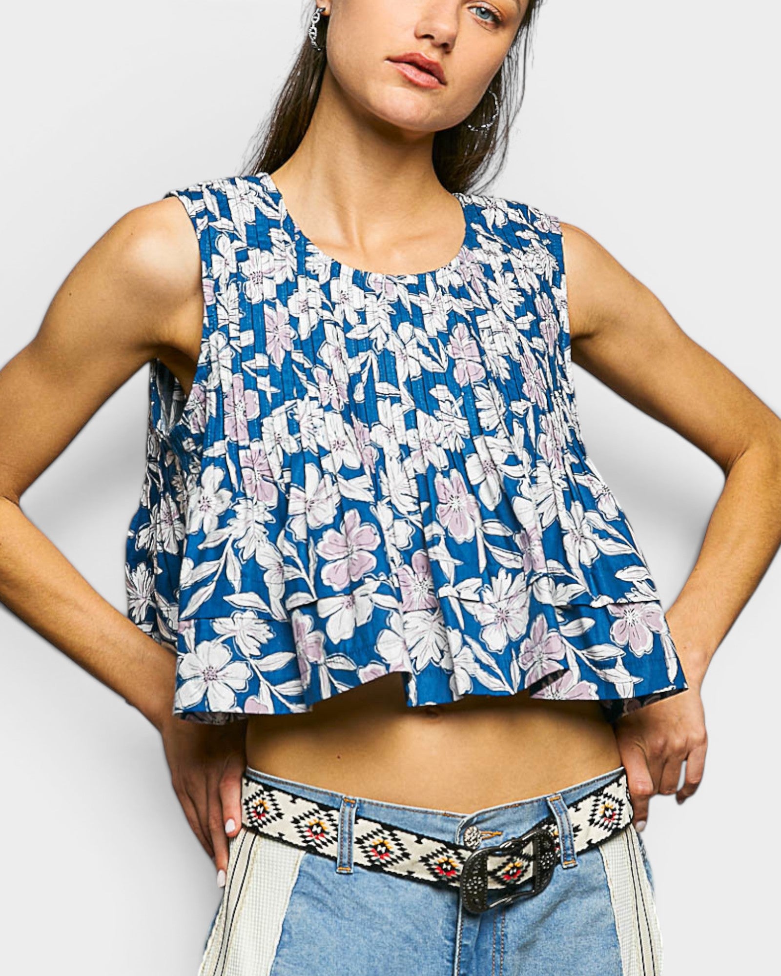 Woman wearing a blue floral sleeveless top against a white background