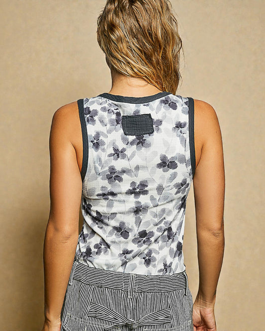 Person wearing a sleeveless floral top against a beige background