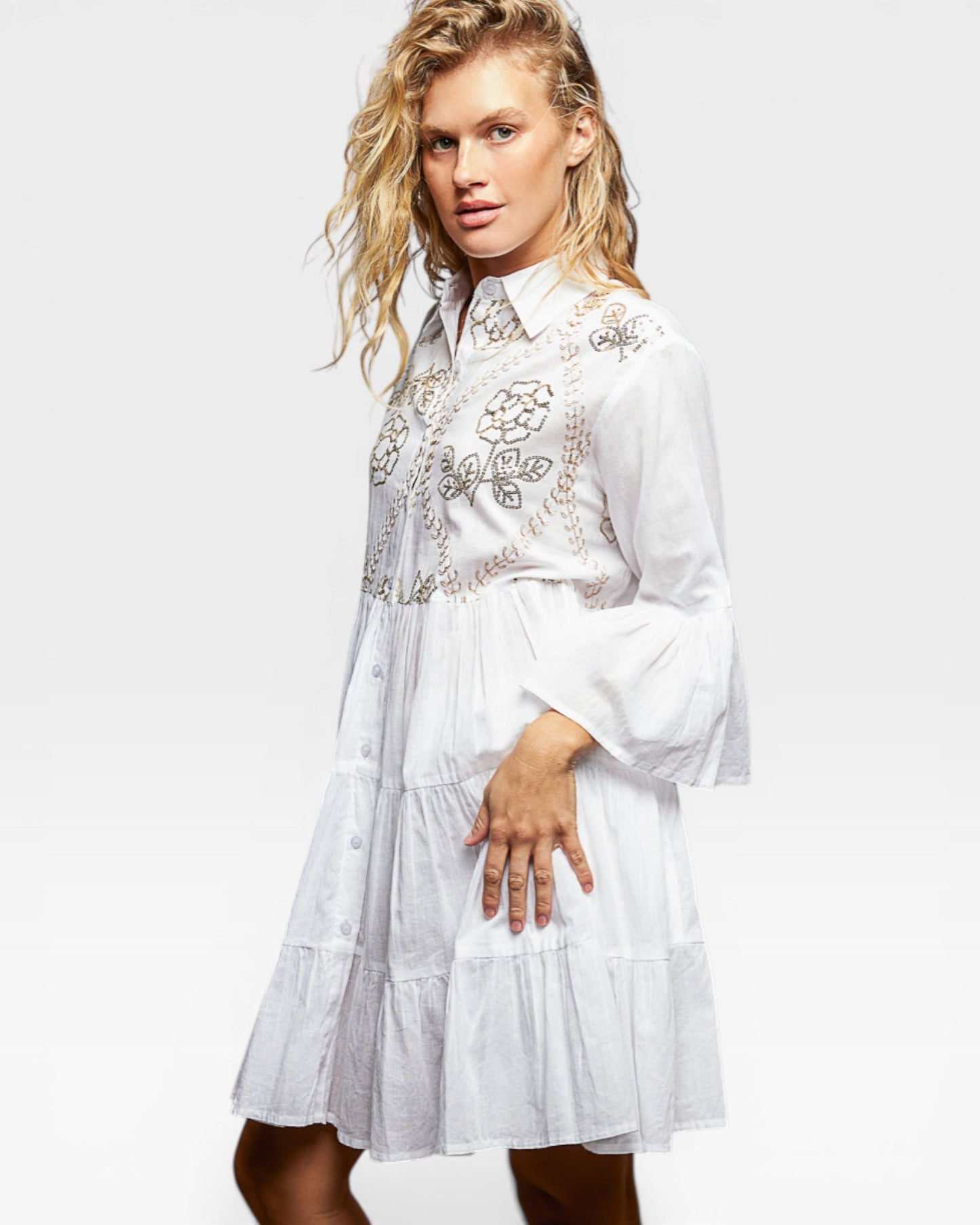 Woman wearing a white dress with floral embroidery on a white background