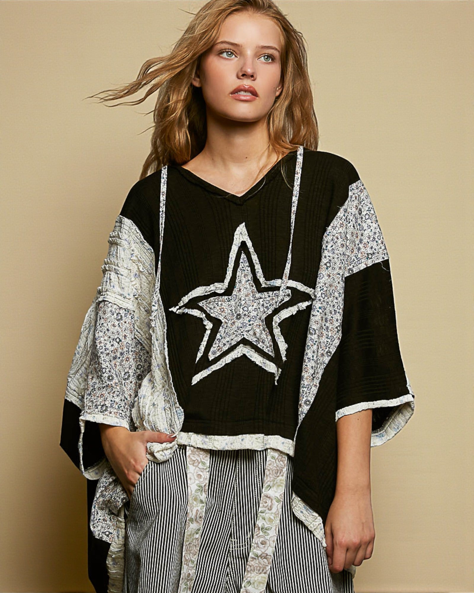 Woman wearing a black sweater with a star design and a patterned cardigan against a beige background
