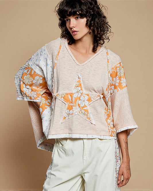 Woman wearing a floral and star patterned top with a beige background