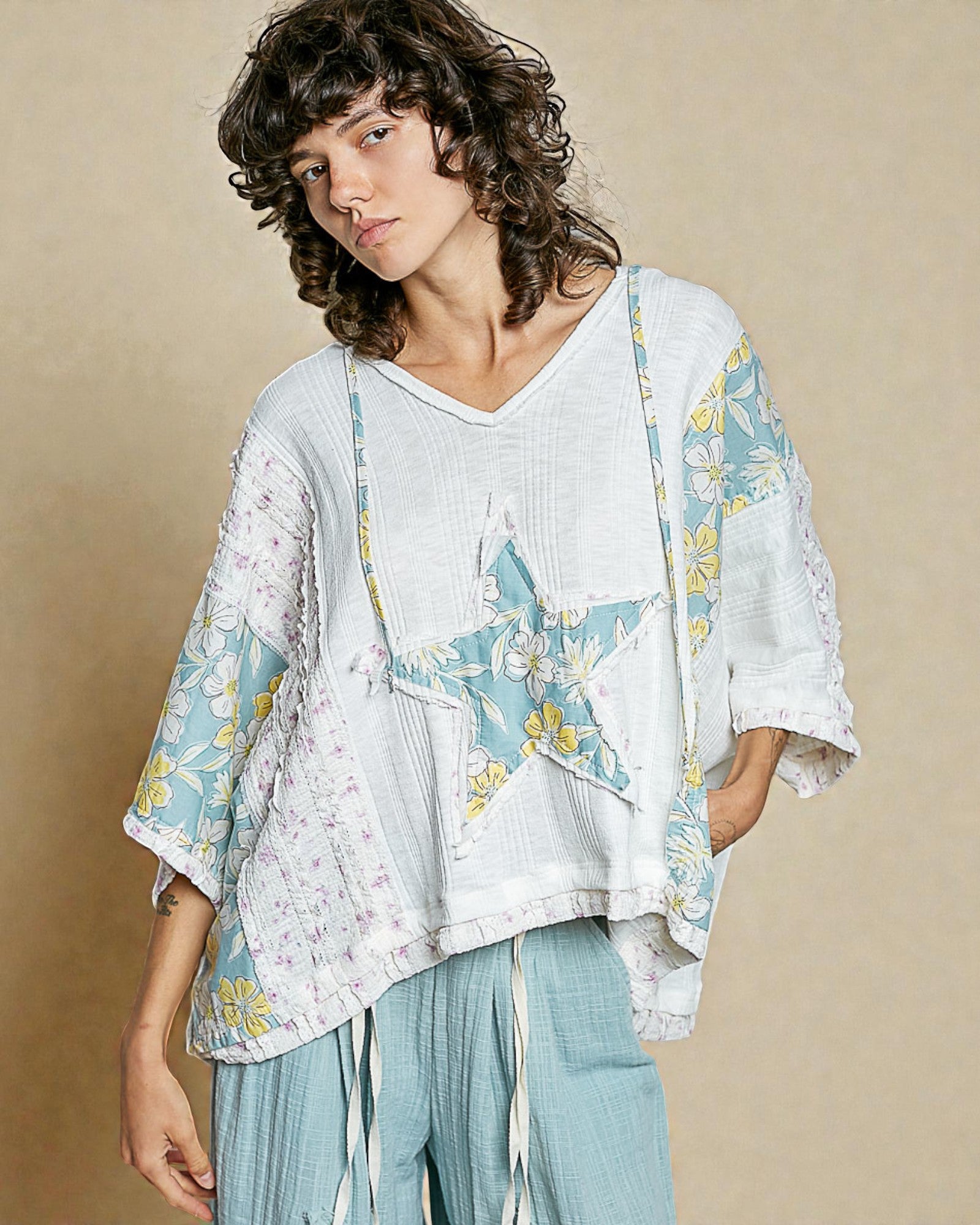 Woman wearing a light-colored outfit with floral patterns on a beige background