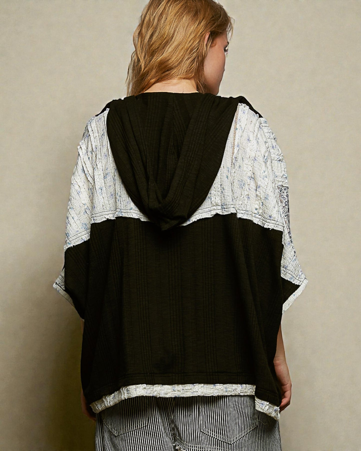 Person wearing a black and white layered outfit against a beige background