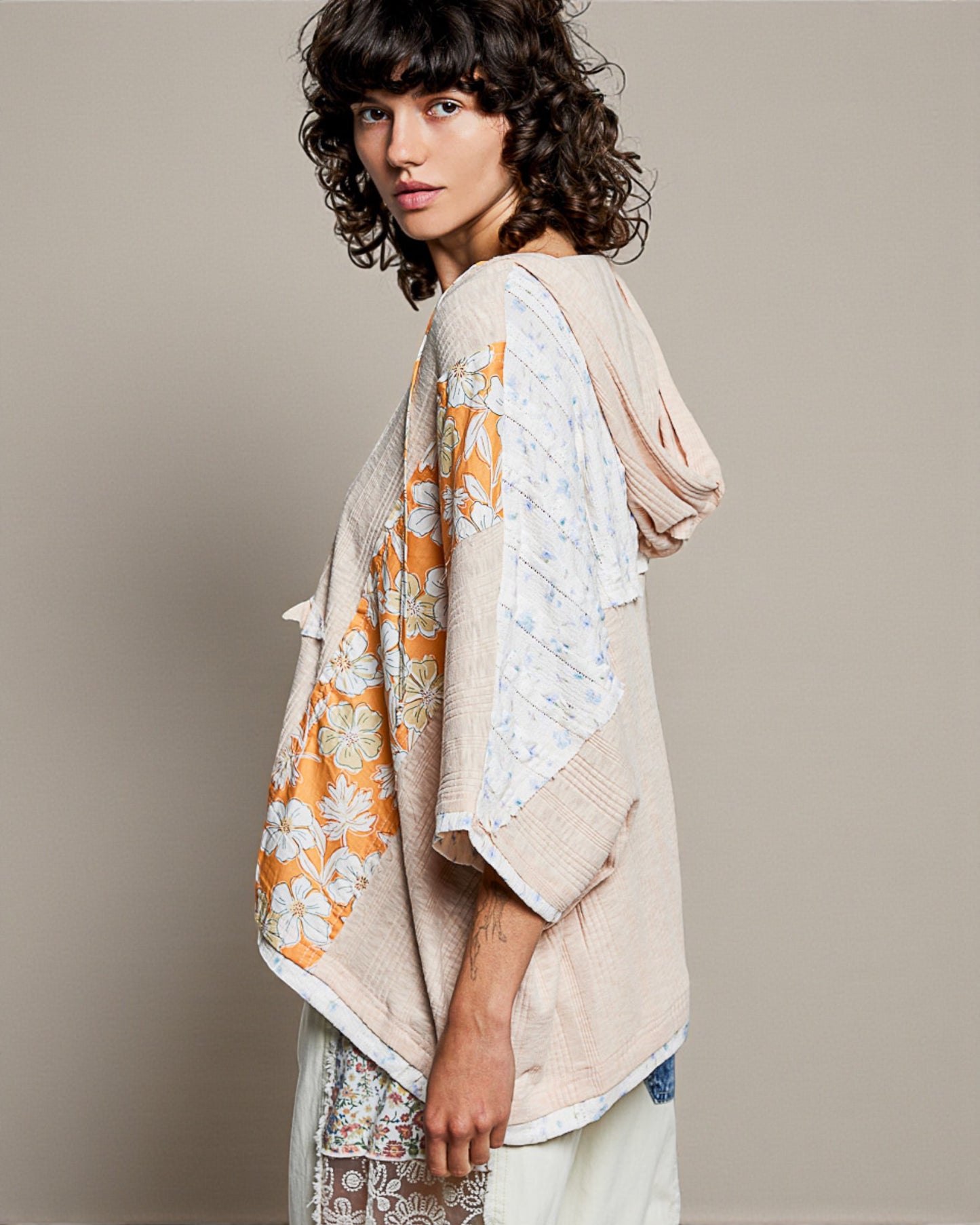 Woman wearing a beige and floral patterned shawl on a plain background