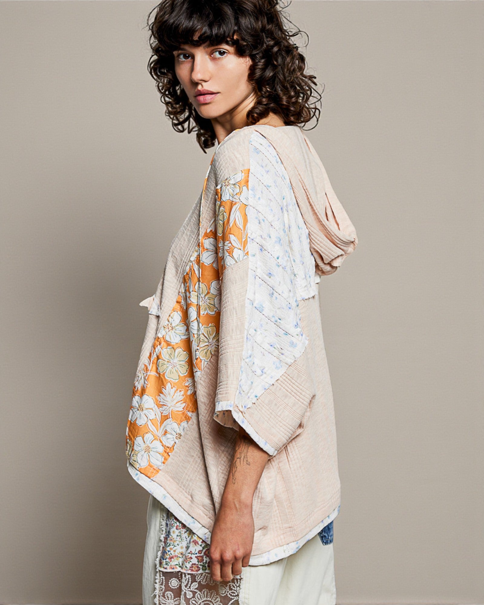 Woman wearing a beige and floral patterned shawl on a plain background