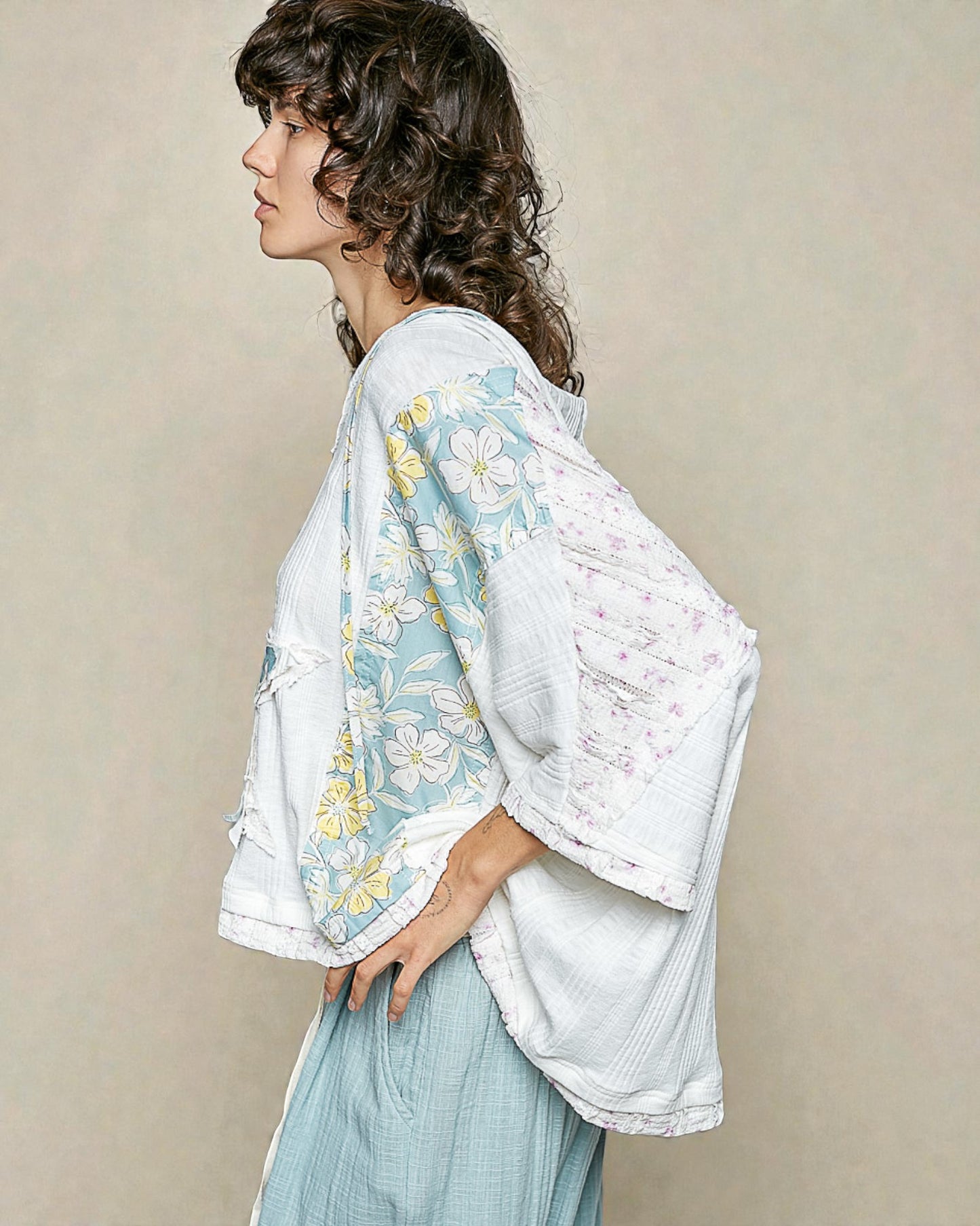 Woman wearing a floral kimono-style garment against a plain background