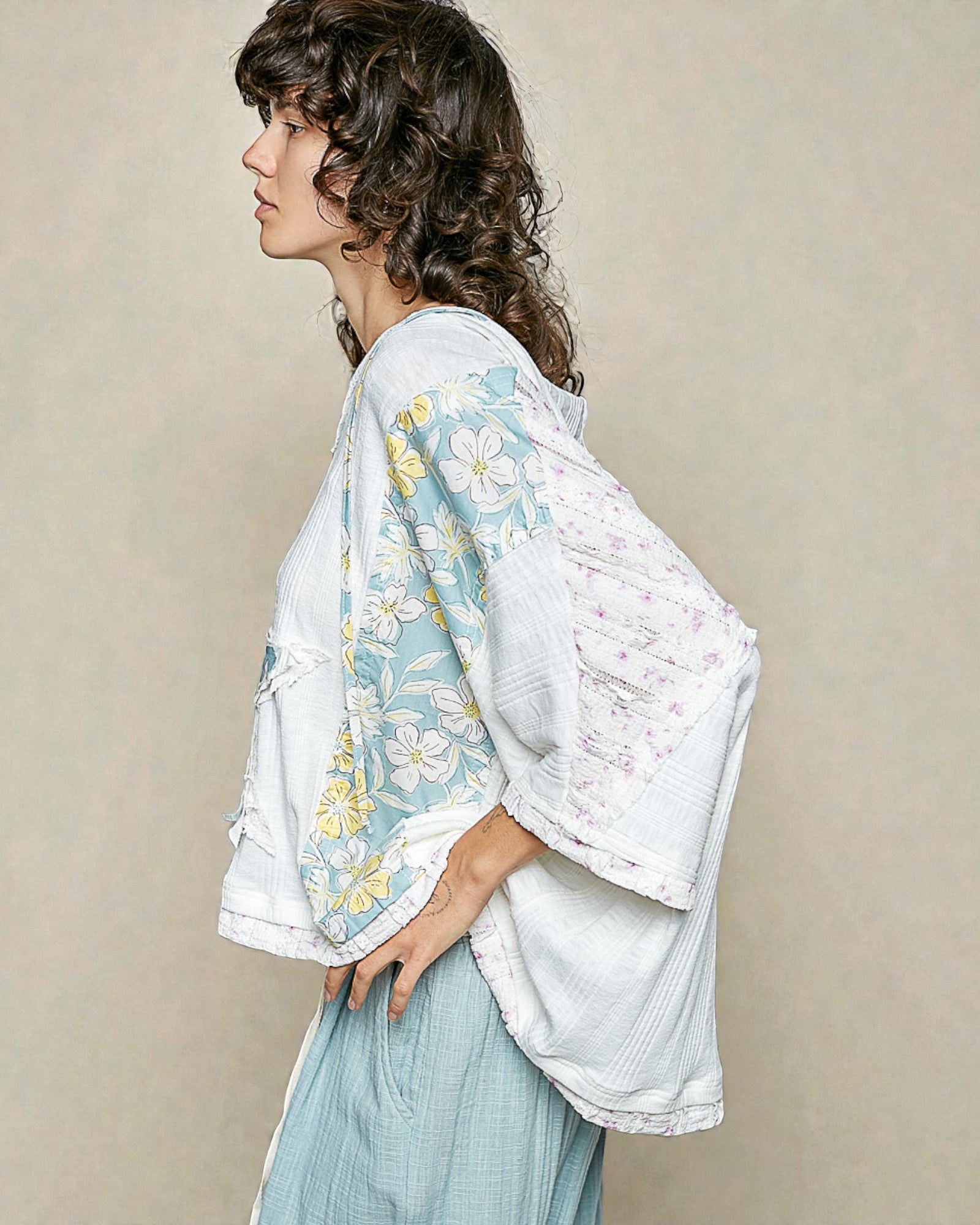 Woman wearing a floral kimono-style garment against a plain background