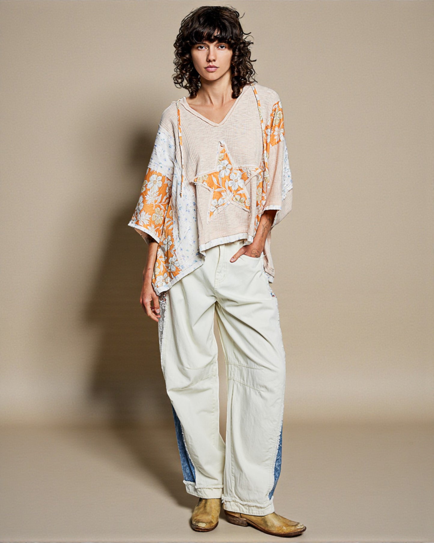 Person wearing a light-colored outfit with floral patterns on a plain background