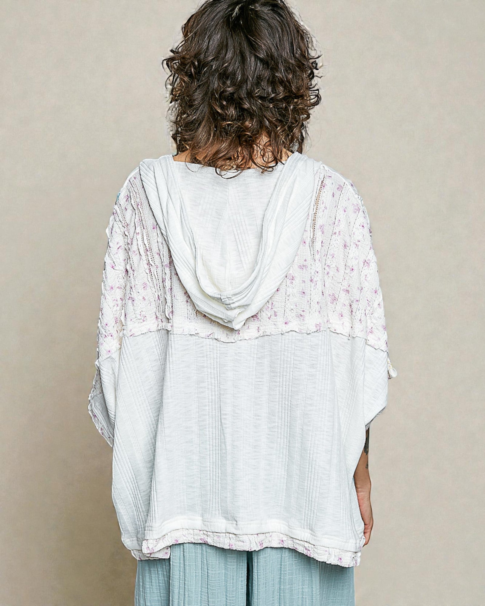 Woman wearing a light blue and white lace top against a beige background