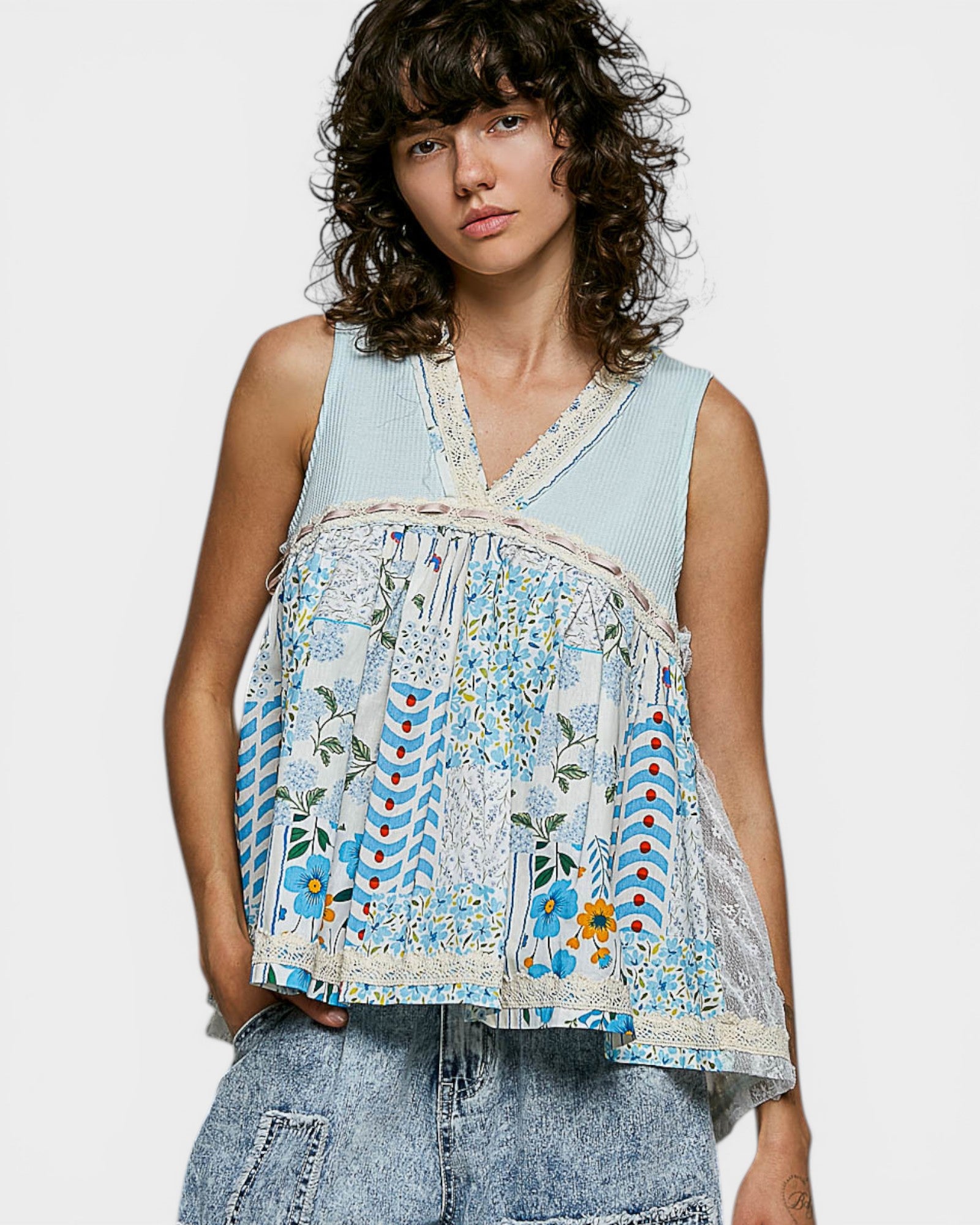 Woman wearing a sleeveless, floral-patterned top with a light blue background