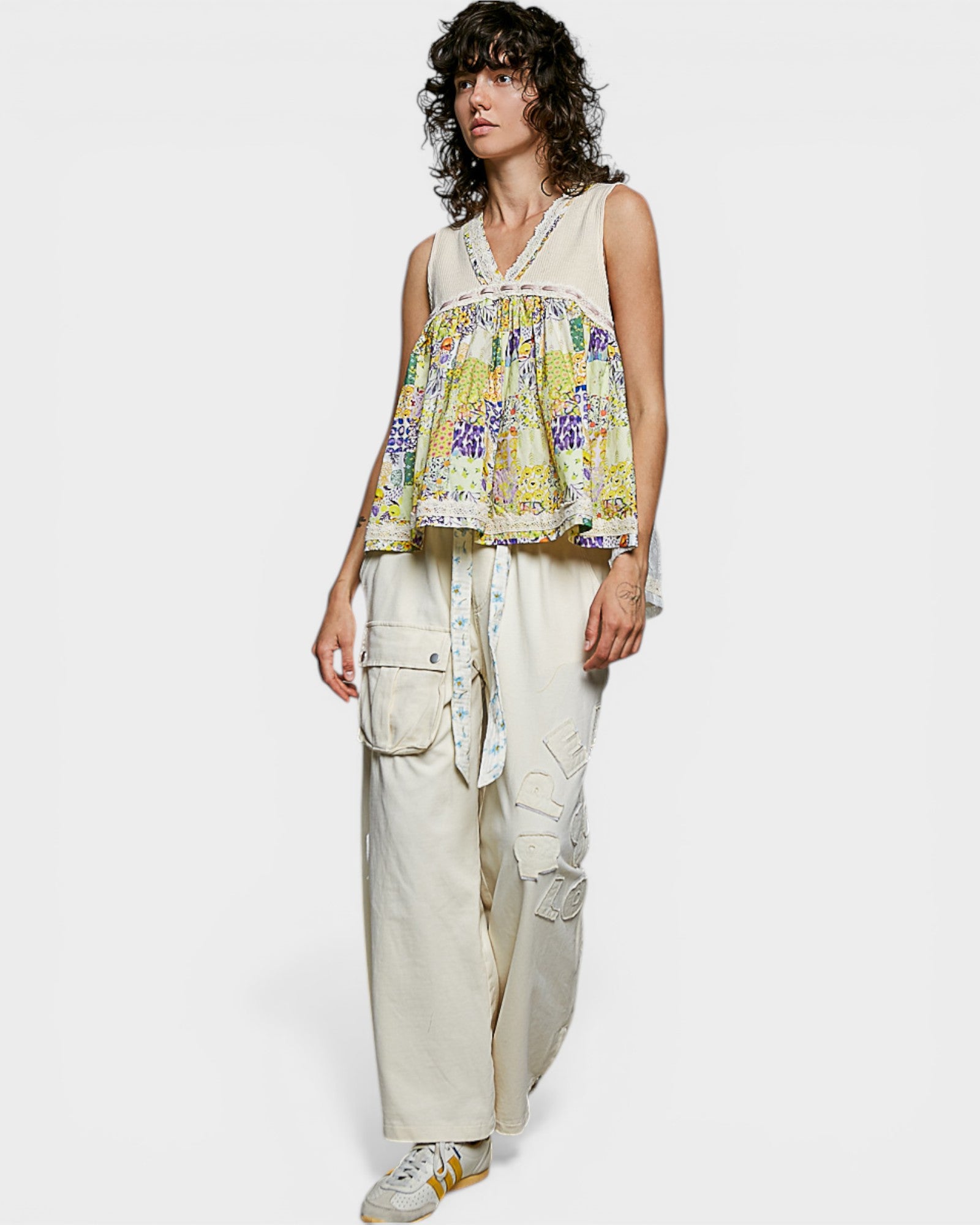 Woman wearing a floral top and beige pants on a white background