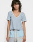 Woman wearing a light blue patterned top with lace details on a white background