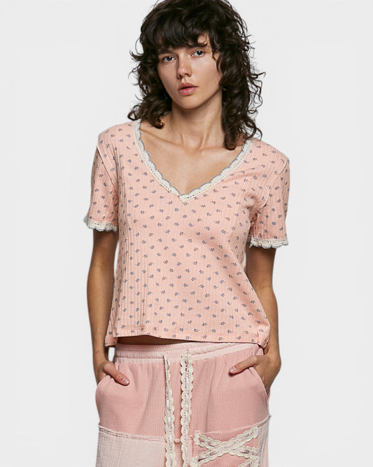 Woman wearing a pink patterned top and pants on a white background