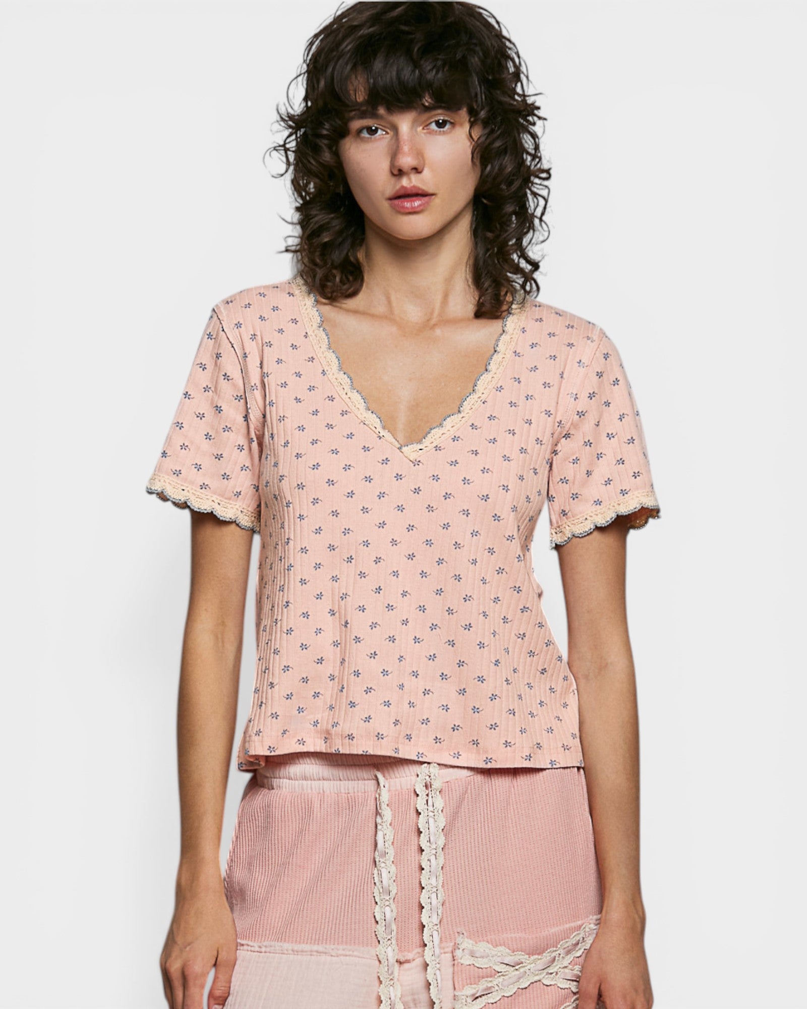 Woman wearing a pink patterned top and pants against a white background