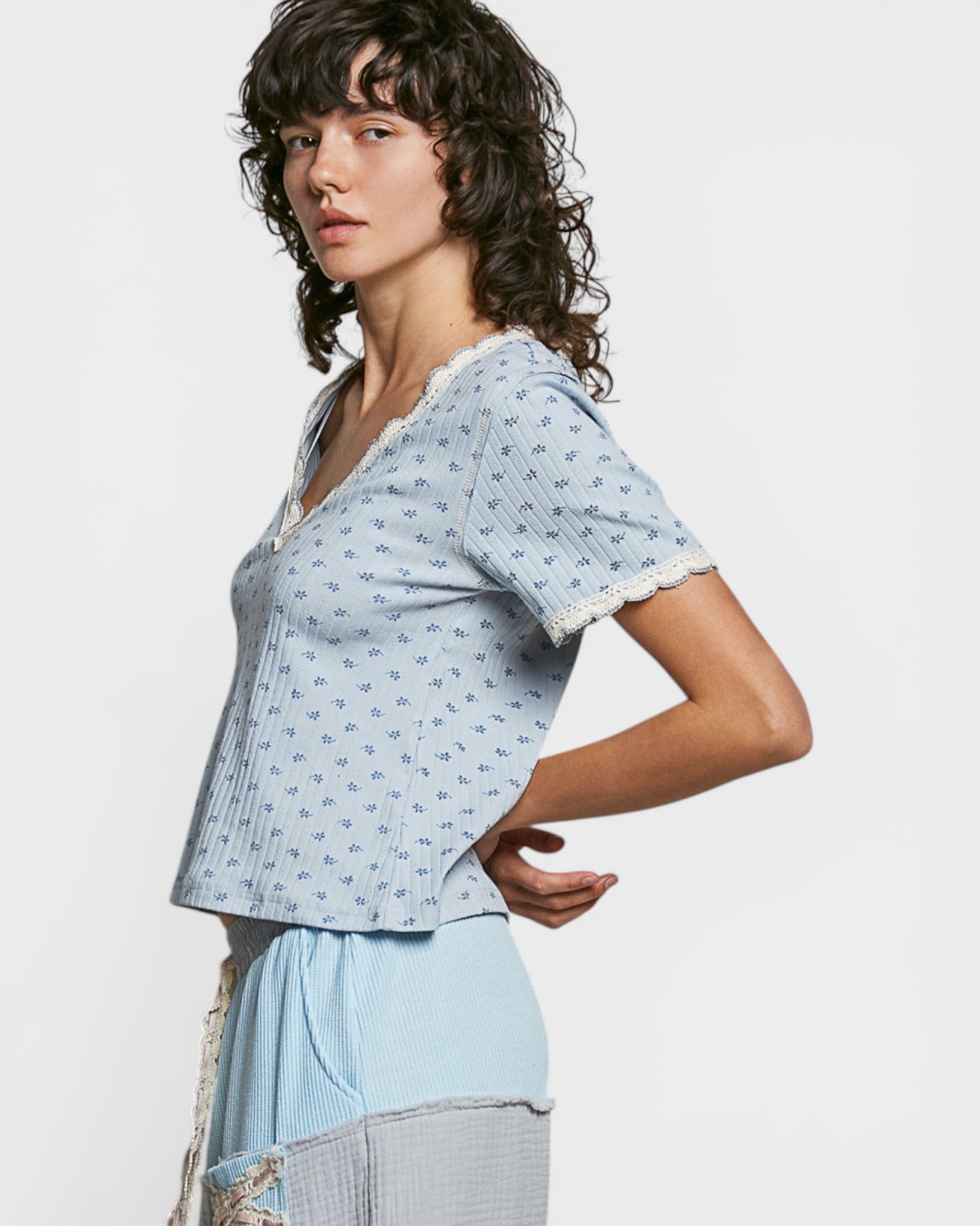 Woman wearing a light blue patterned top with lace trim on a white background