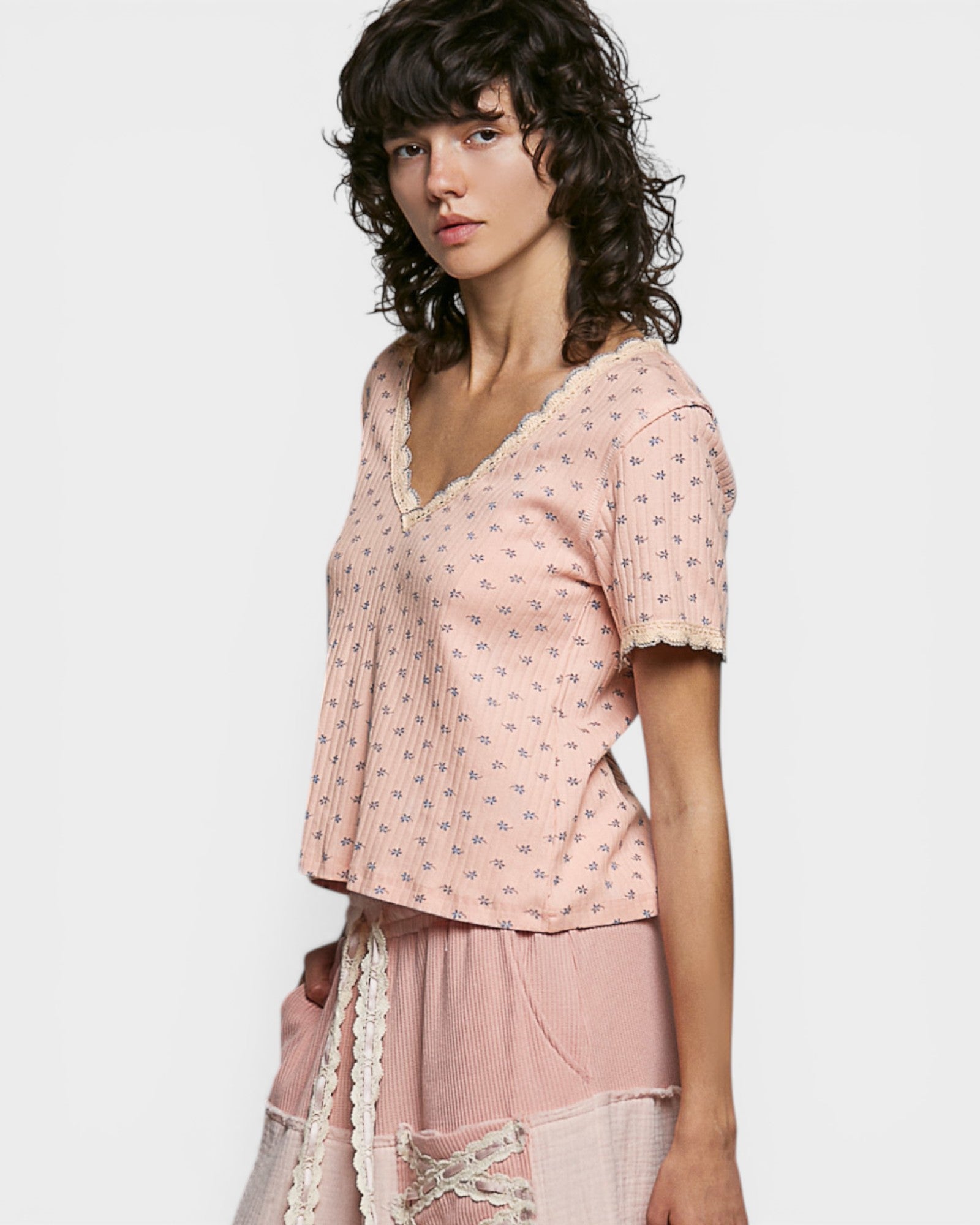 Woman wearing a pink patterned top and skirt on a white background