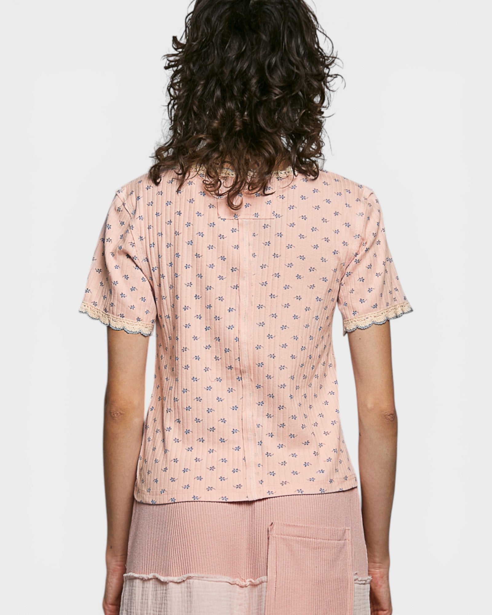 Person wearing a pink patterned top and pants on a white background