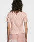 Person wearing a pink patterned top and pants on a white background