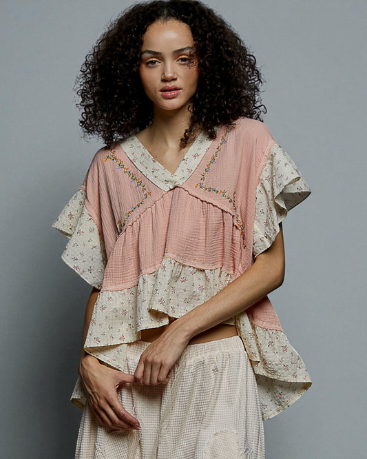 Woman wearing a layered outfit with a pink top and white skirt against a gray background