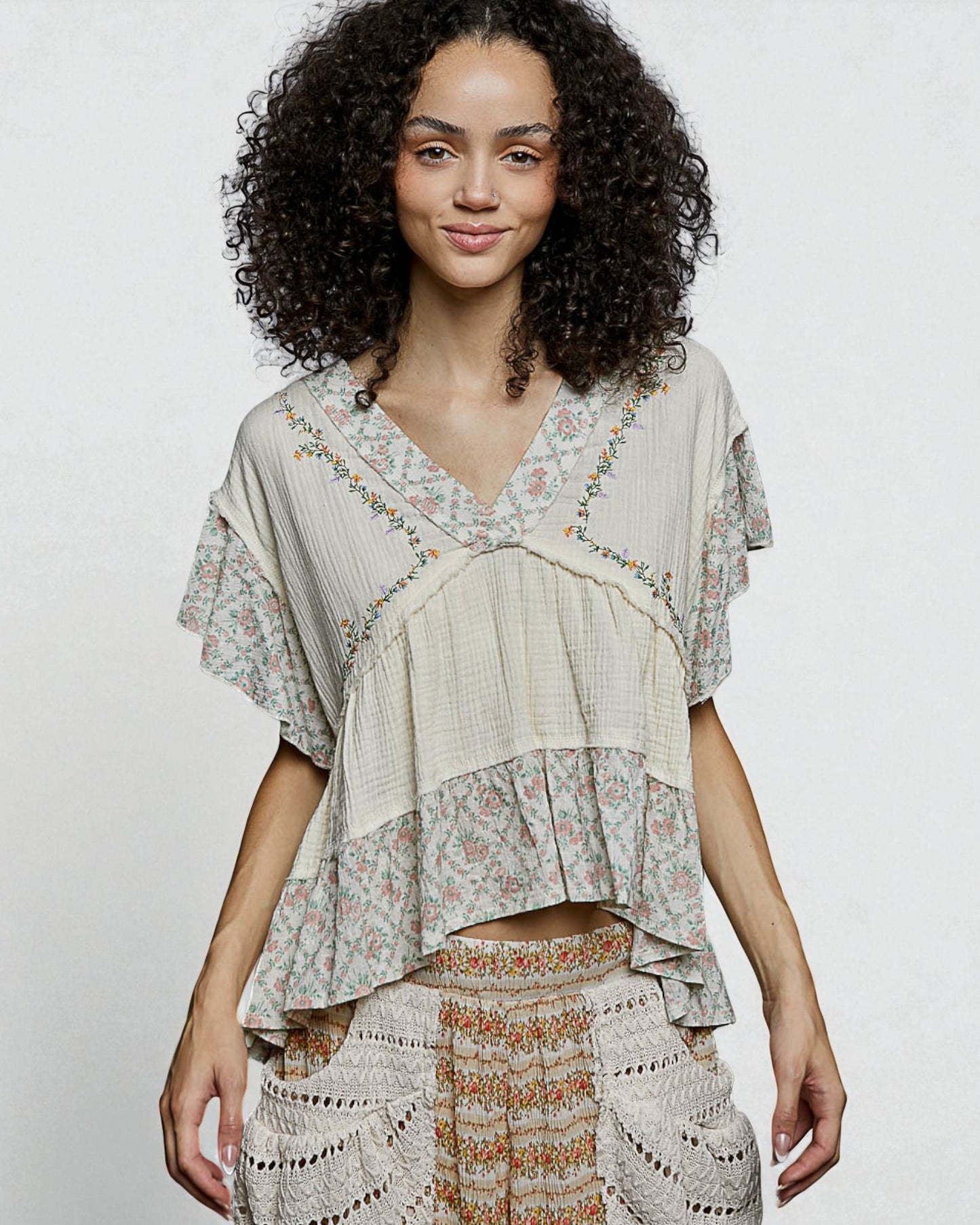 Woman wearing a layered, patterned top against a plain background