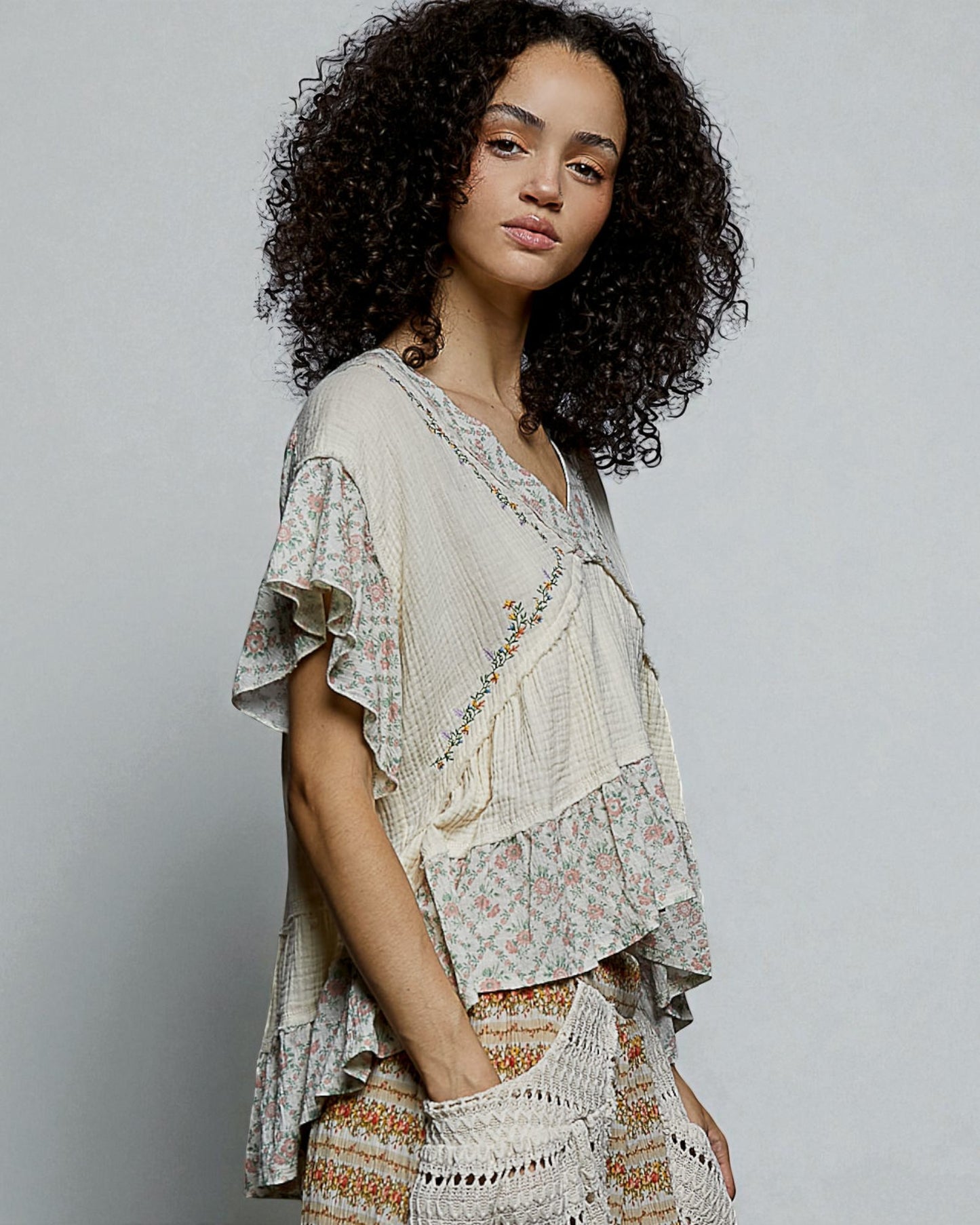 Woman wearing a layered, patterned outfit against a plain background