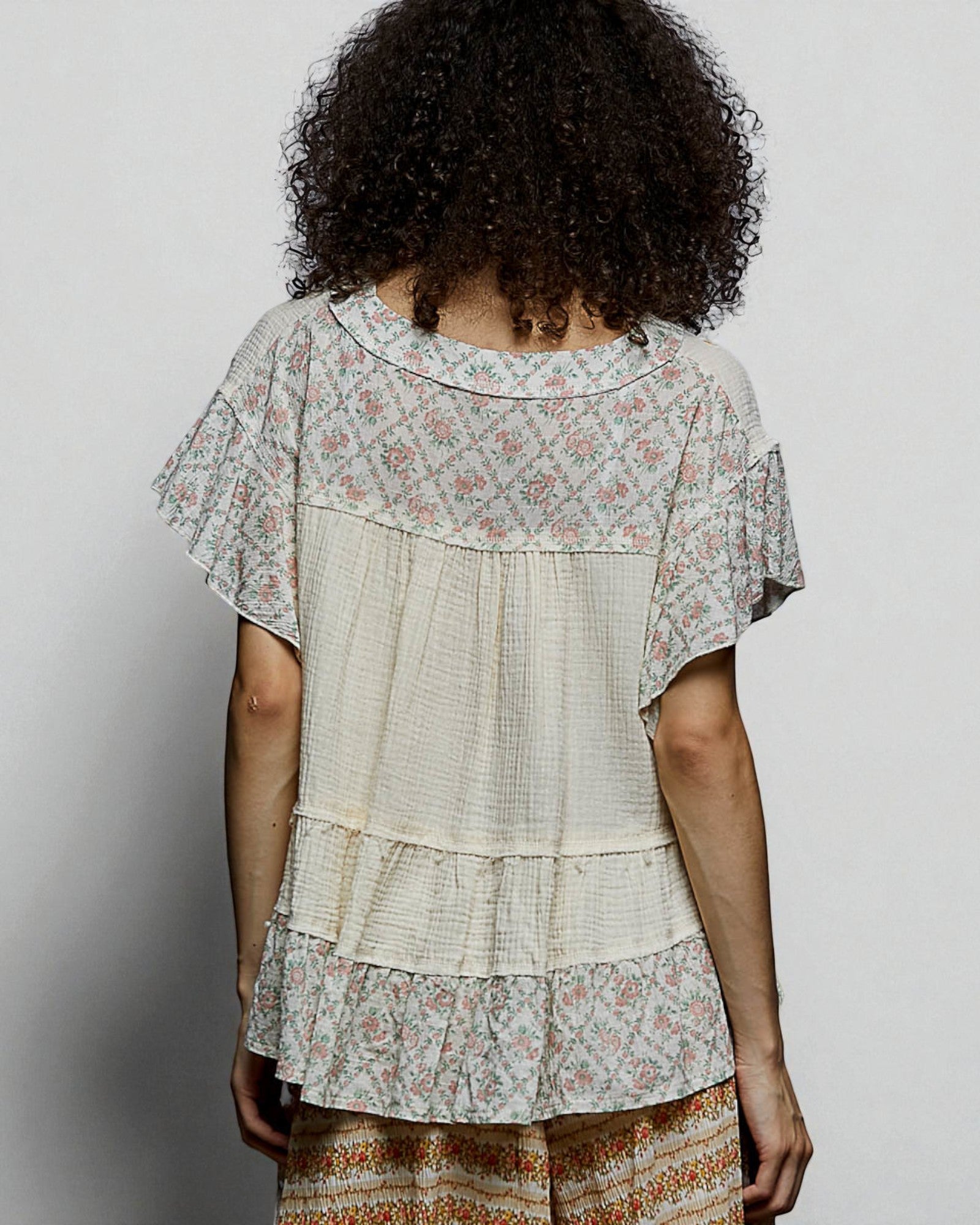 Person wearing a layered, floral-patterned dress against a plain background