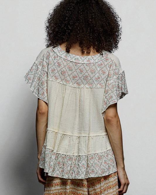 Person wearing a layered, floral-patterned dress against a plain background