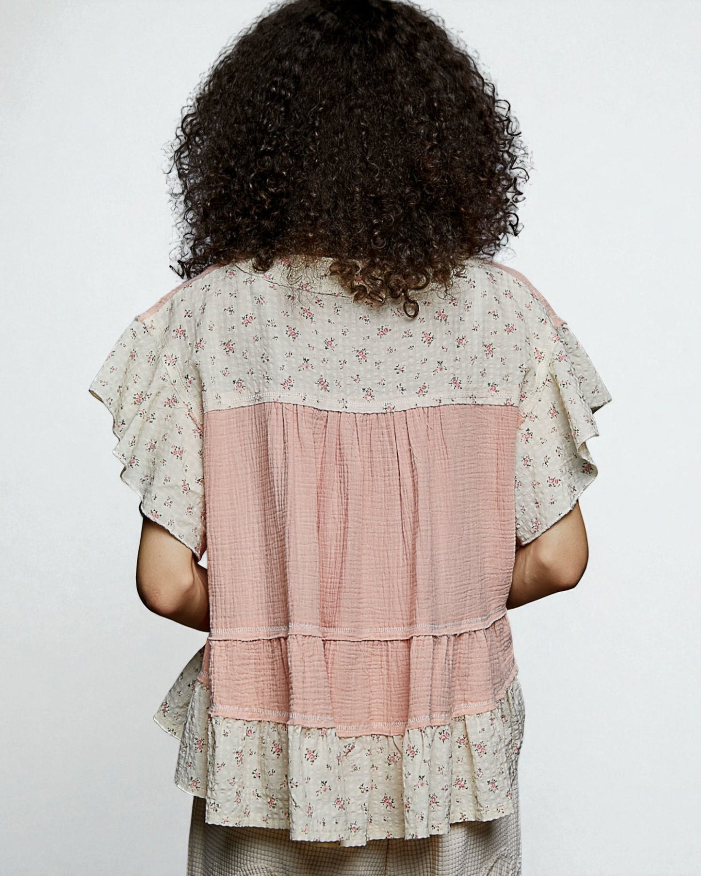 Person wearing a layered dress with floral patterns on a plain background