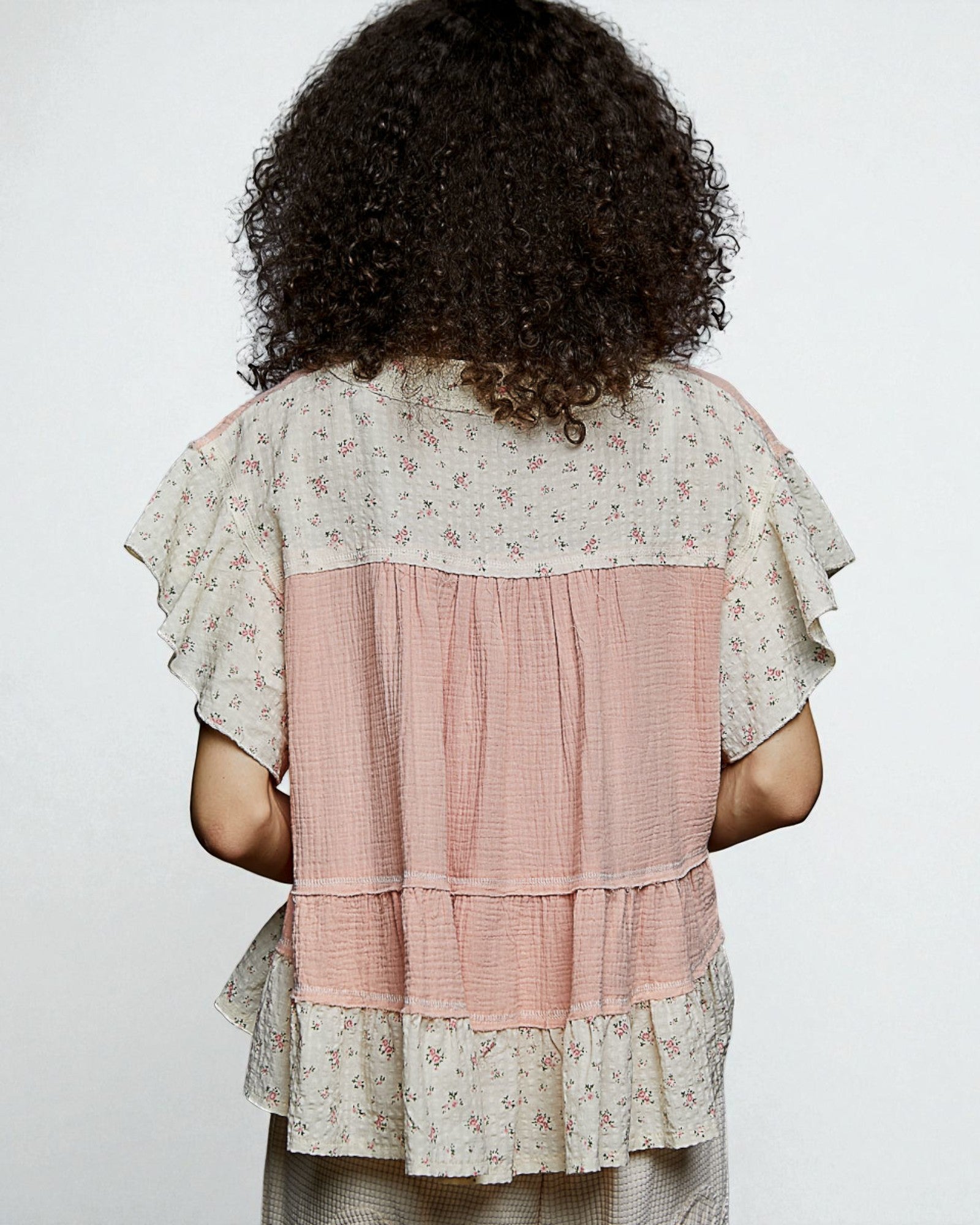 Person wearing a layered dress with floral patterns on a plain background