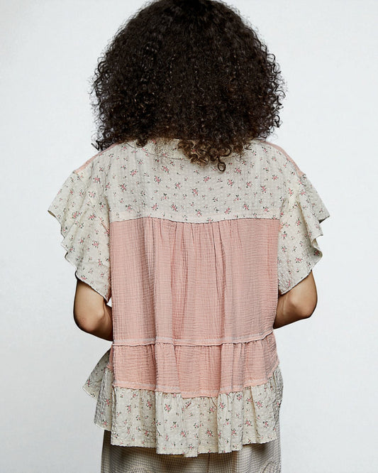 Person wearing a layered dress with floral patterns on a plain background