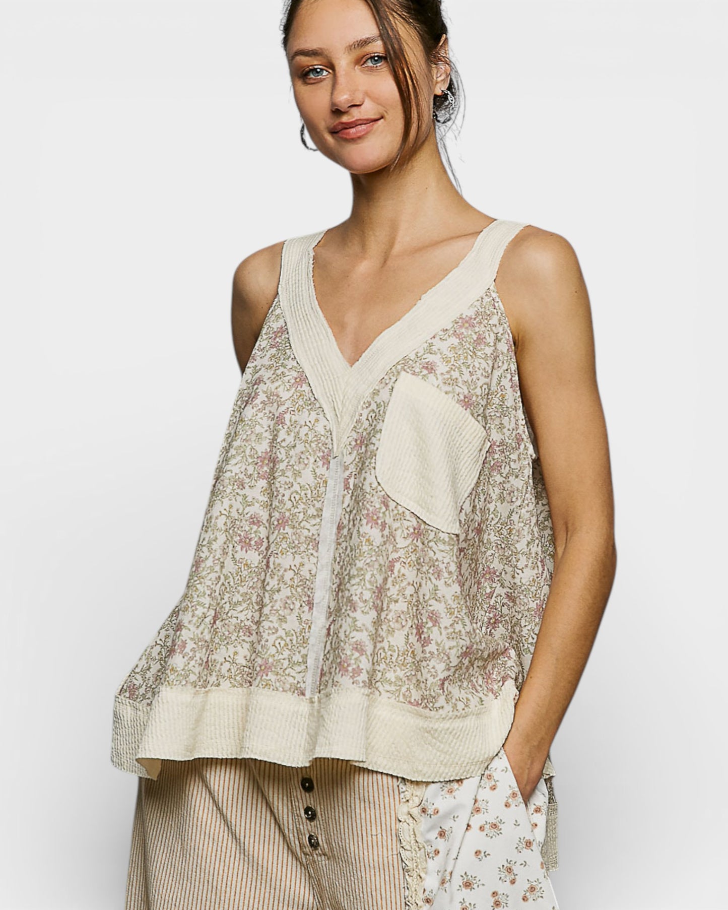 Woman wearing a floral sleeveless top with a plain white background