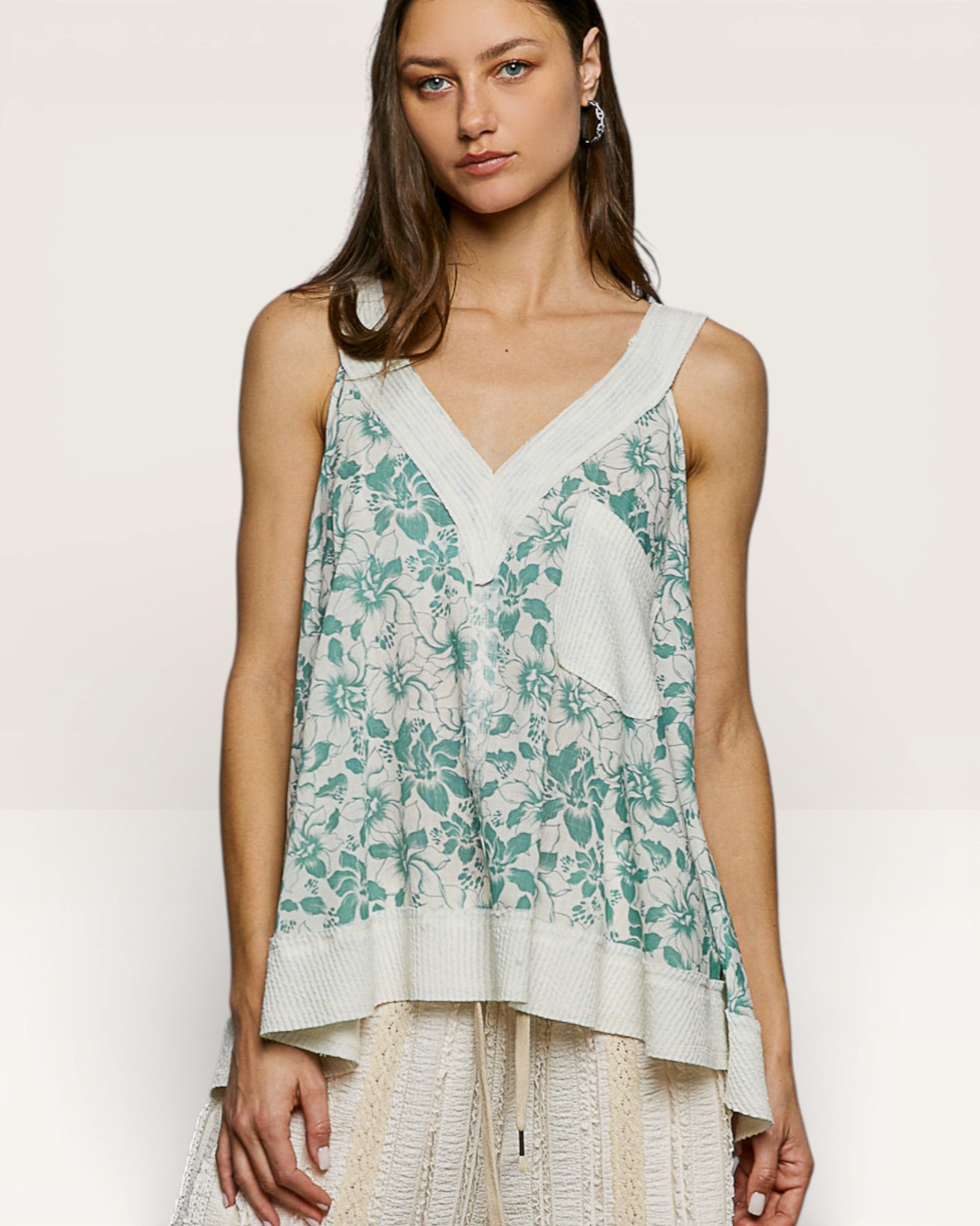 Woman wearing a floral sleeveless top with a plain white background