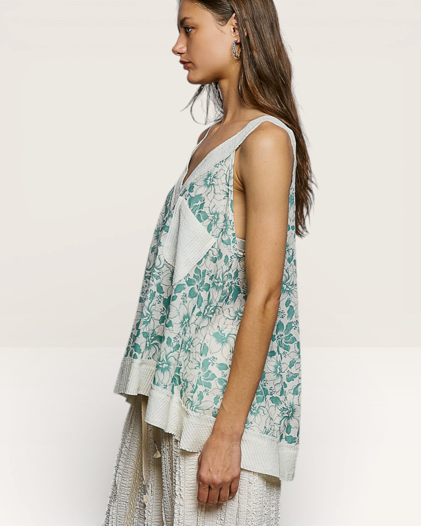 Woman wearing a floral sleeveless top with a plain background