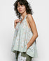 Woman wearing a light green floral sleeveless top against a white background