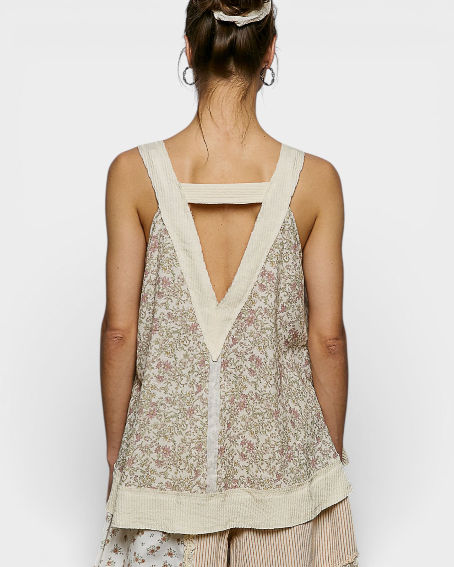 Woman wearing a floral sleeveless top with a V-neckline on a white background